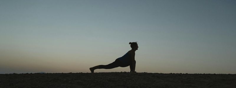 Silhouetted figure practicing balance exercises against a dim background